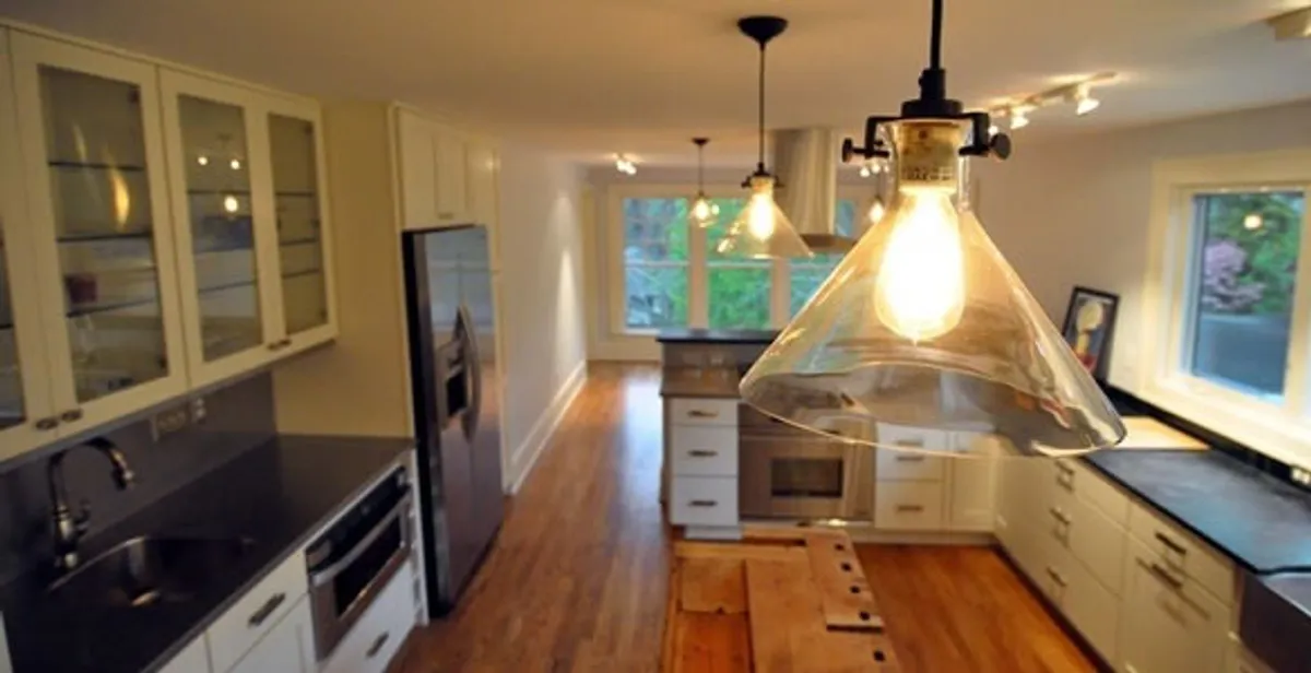 Residential electrician installing modern indoor light fixture in a home in Des Moines, IA
